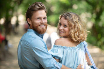 Obraz premium young woman and man walking in city park holding hands