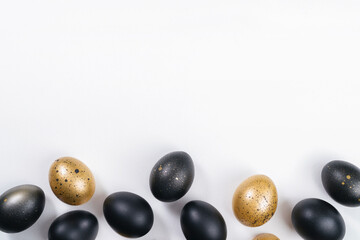 Eggs painted gold and black on white background. Minimal Easter concept with copy space for text. Golden luxury backdrop
