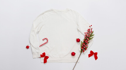 Close up white blank template sweatshirt copy space. Christmas Holiday concept. Top view mockup sweatshirt. Red holidays decorations on white background. Happy New Year accessories. Xmas outfit