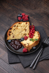 Traditional Italian Christmas or Easter fruitcake panettone with raisins, candied, berries and berry jam