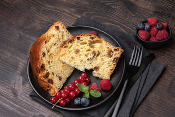 Traditional Italian Christmas or Easter fruitcake panettone with raisins, candied, berries and berry jam
