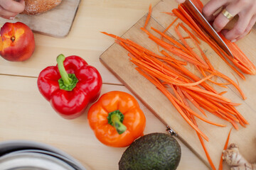 Overhead view of woman julienning carrot on table
