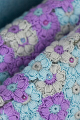 Fototapeta na wymiar Crocheted handmade pillowcases with light blue, violet and grey flower pattern in interior