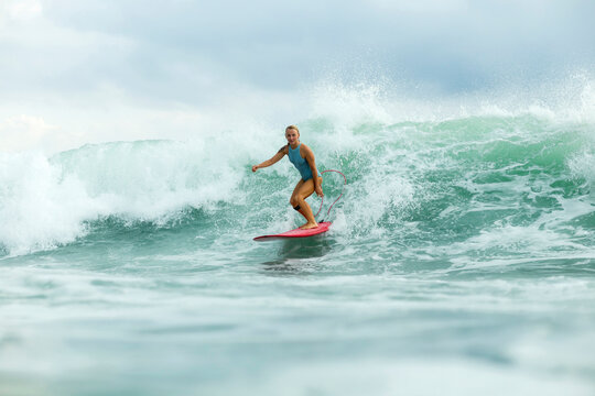 Woman surfing in sea against cloudy sky