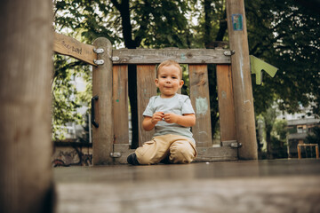 Obraz premium a child of 2-3 years old walks on the playground and sits on top of a wooden slide