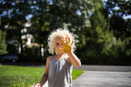 Playful girl showing painted hand while standing in lawn - Powered by Adobe