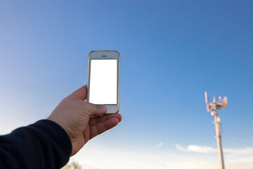 Man holds mobile phone on hand pointing to telephony antenna