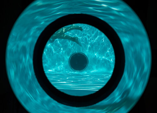 A swimmer's legs can be seen through a portal on the side of the pool.