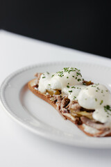 sandwich with poached egg and stew, drizzled with cheese and herbs