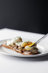 sandwich with poached egg and stew, drizzled with cheese and herbs