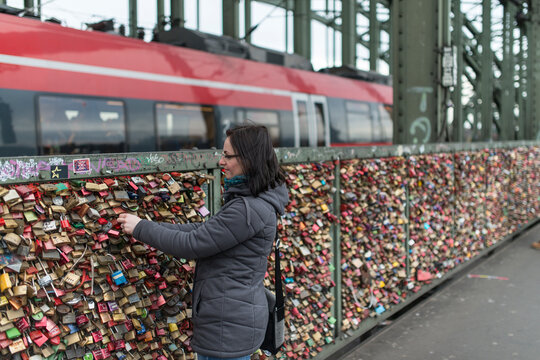 Woman adds lock to fence of locks, train station