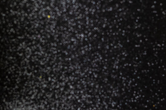 Fundo preto natalino cheio de brilhos de gliter. Fundo preto com brilhos desfocados.