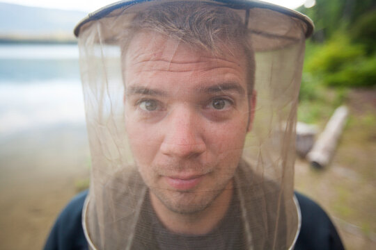 Portrait of a man wearing a mosquito head net.