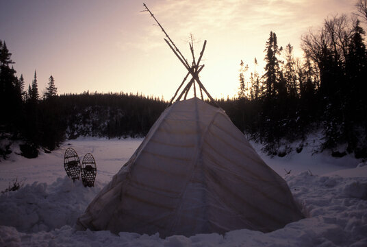 Winter sunset over a teepee in snow.