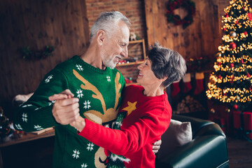 Side profile photo of old age couple seniors wear festive ugly sweaters hands together dancing...