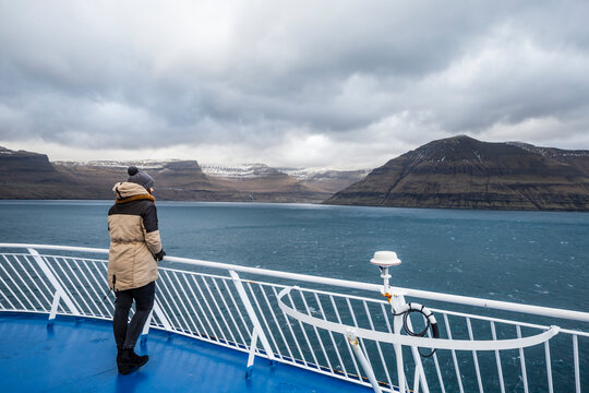 Woman looking at view of fjords from ship, Faroe Islands, Denmark