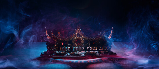 Fabulous golden crown of the king on a dark background. Panoramic view of the abstract fog. Mockup for your logo. 