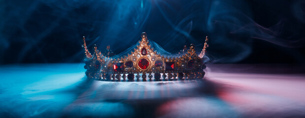 Fabulous golden crown of the king on a dark background. Panoramic view of the blue and red fog....