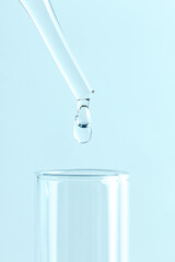 Close-up of a laboratory glass pipette with liquid drop on white background. Concept of medical or science laboratory.