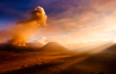 Mt. Bromo volcano erupting with strong god rays in the foreground.
