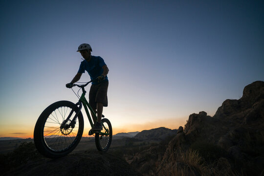 A man performs trial bike standing on a rock at El Diente, Jalisco, Mexico.