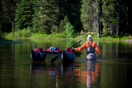 A fisherwoman wades with her pontoon boat in the Cascade mts. of Washington State.
