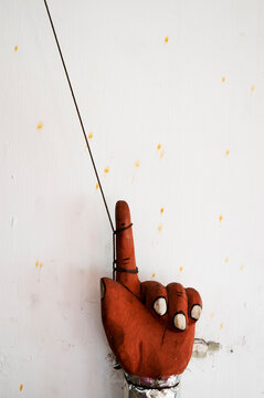 Moden puppet hand with string against a white wall.