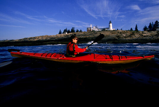 Man kayaking in front of Pemaquid Point light house, Maine, USA