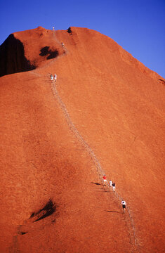 Hikers make their way up Uluru or Mt. Ayers in the Australian Outback.