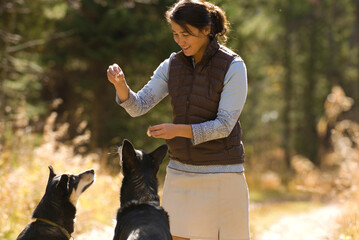 A young woman gives her dogs treats while walking in Jackson Hole, Wyoming.