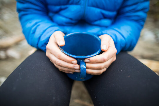 Mountaineer holds mug of hot tea at basecamp.