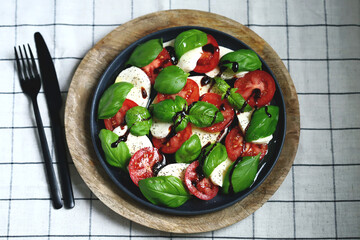 Italian signature caprese salad on a black plate.
