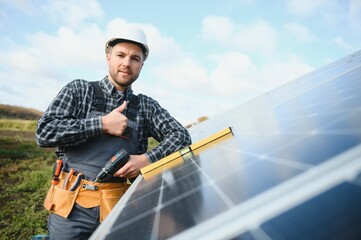 Naklejka premium Male worker in uniform outdoors with solar batteries at sunny day.