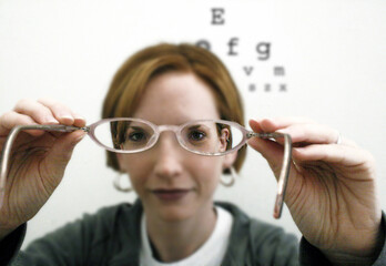 An optometrist putting a pair of glasses on for a patient.