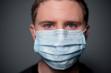 Studio closeup portrait of 17 year old Caucasian man wearing a medical mask.