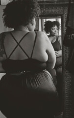 Black woman looking in mirror admiring herself