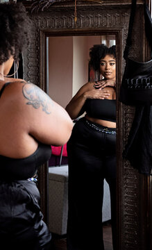 Black woman looking in mirror admiring herself