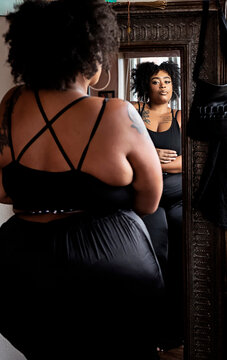 Black woman looking in mirror admiring herself