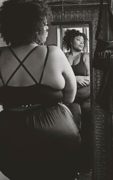 Black woman looking in mirror admiring herself