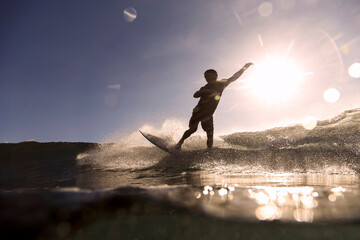 Surfer on a wave at sunset time