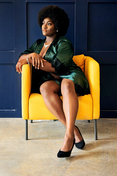 Black woman with afro sitting in yellow chair