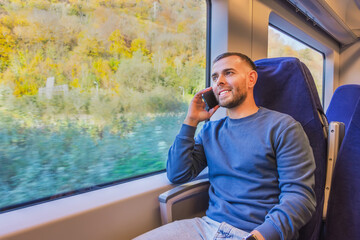 Middle aged man is talking on the phone and smiling and looking, enjoying the view of nature and forest in highland river valley.