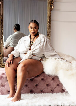 Plus size Black woman sitting on bench wearing boyfriend shirt and panty