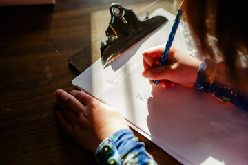 close-up of a small child sitting in a patch of light doing homework