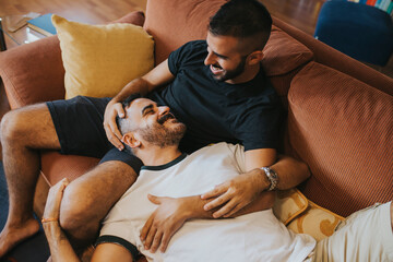 boy lying on his boyfriend on the sofa. they look happy