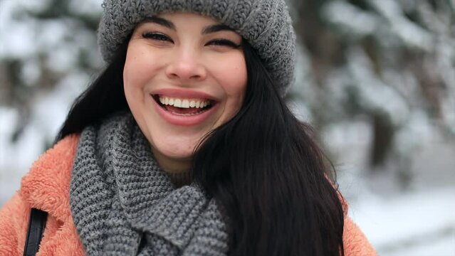 Outdoor close-up female model with romantic smile chilling in park in winter day. Long haired woman laughing while posing on snow background. 