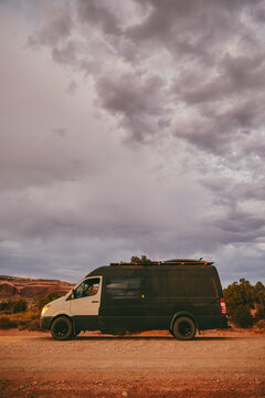 Camper van off side of dirt road during golden sunset in Moab, Utah.