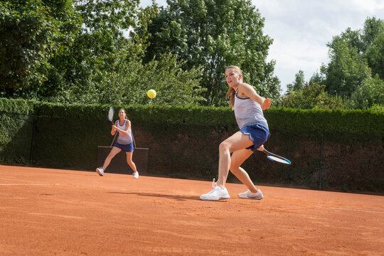 Two women playing tennis on a sunny day, Bavaria, Germany
