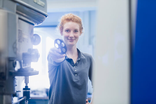 Young female engineer holding gear in an industrial plant, Freiburg im Breisgau, Baden-W&uuml;rttemberg, Germany