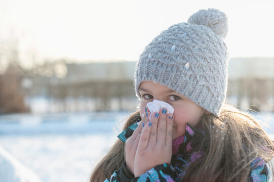 Portrait of girl sneezing in winter